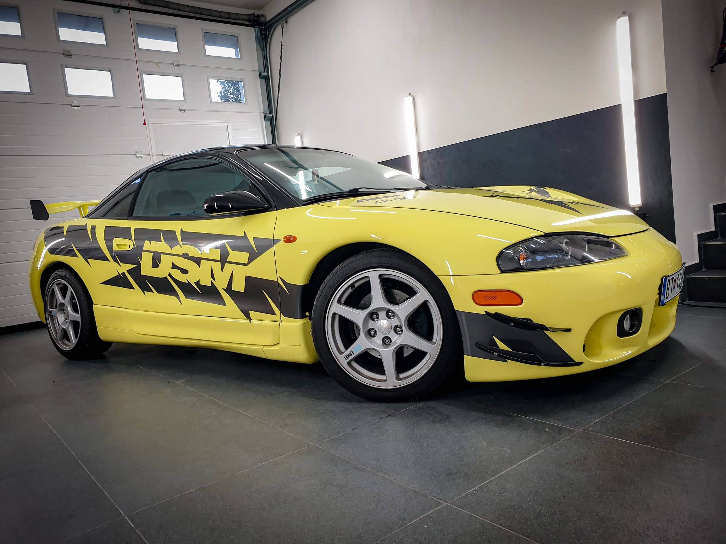 Žlté Mitsubishi Eclipse s čiernym polepom DSM v garáži